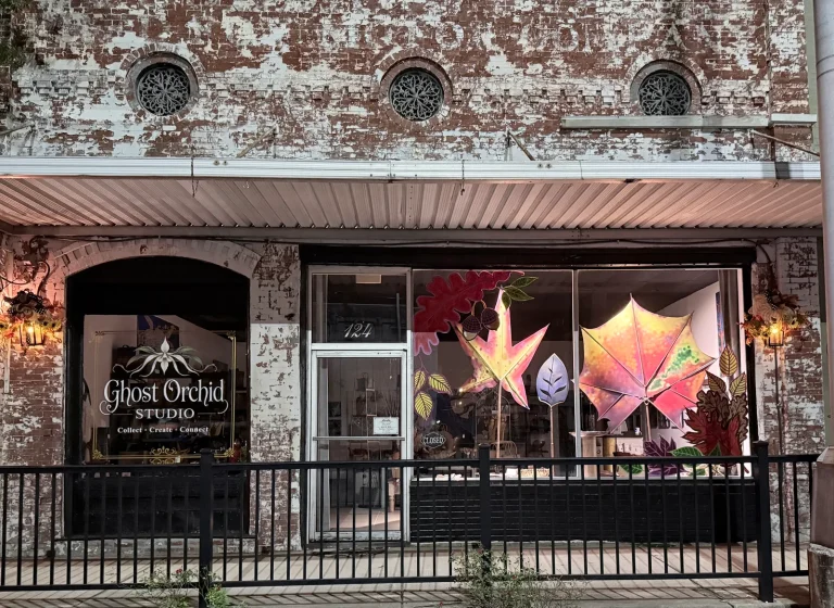 Ghost Orchid Studio's brick storefront with illuminated star and leaf sculptures in the window